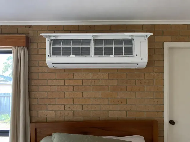 Clean split system with open front panel and visible filters on a brick bedroom wall in Elizabeth North